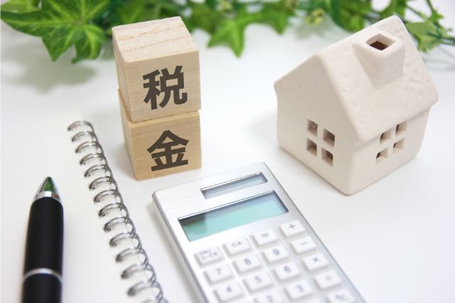 家の模型の前で税金の計算をする人